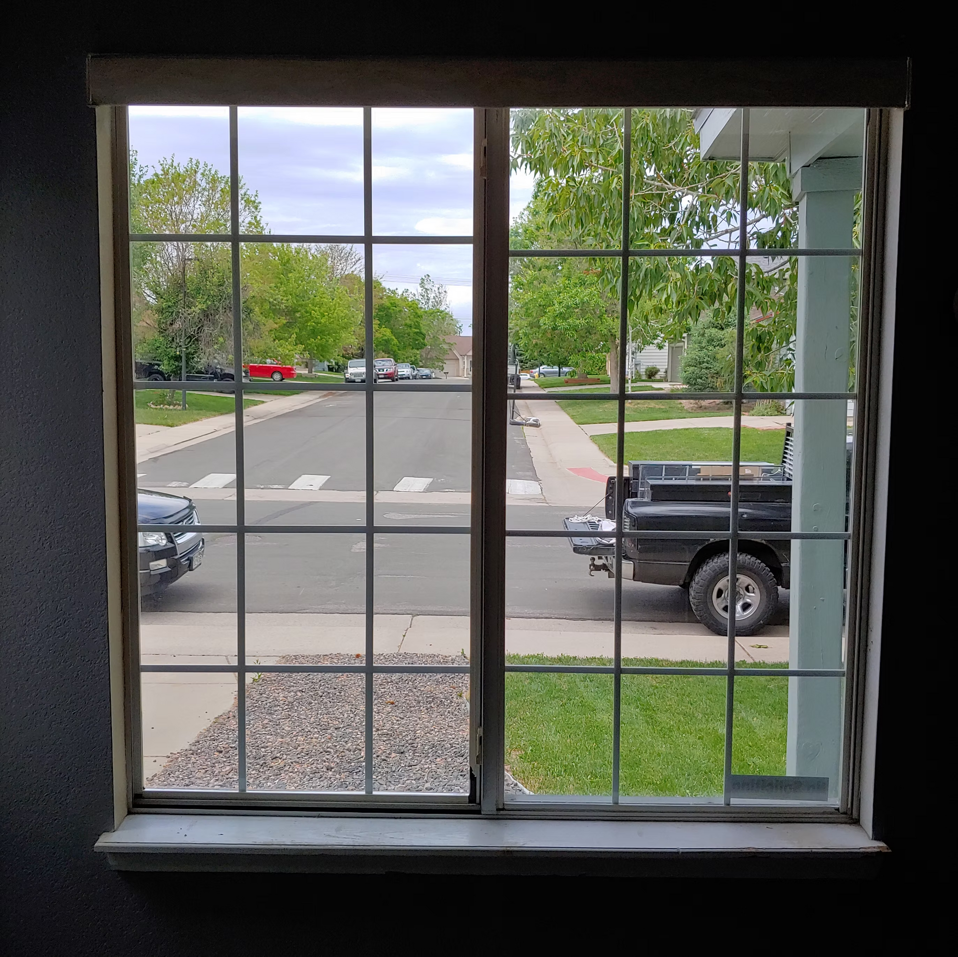 A truck is parked on the side of the road in front of a window.