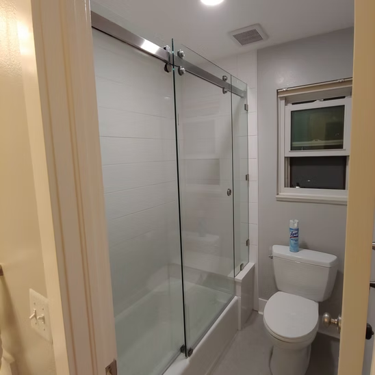 A bathroom with a sliding glass shower door and a toilet