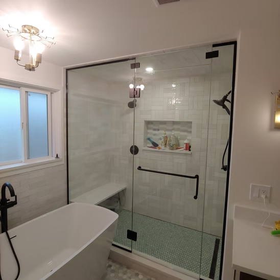 A bathroom with a bathtub and a glass shower door.