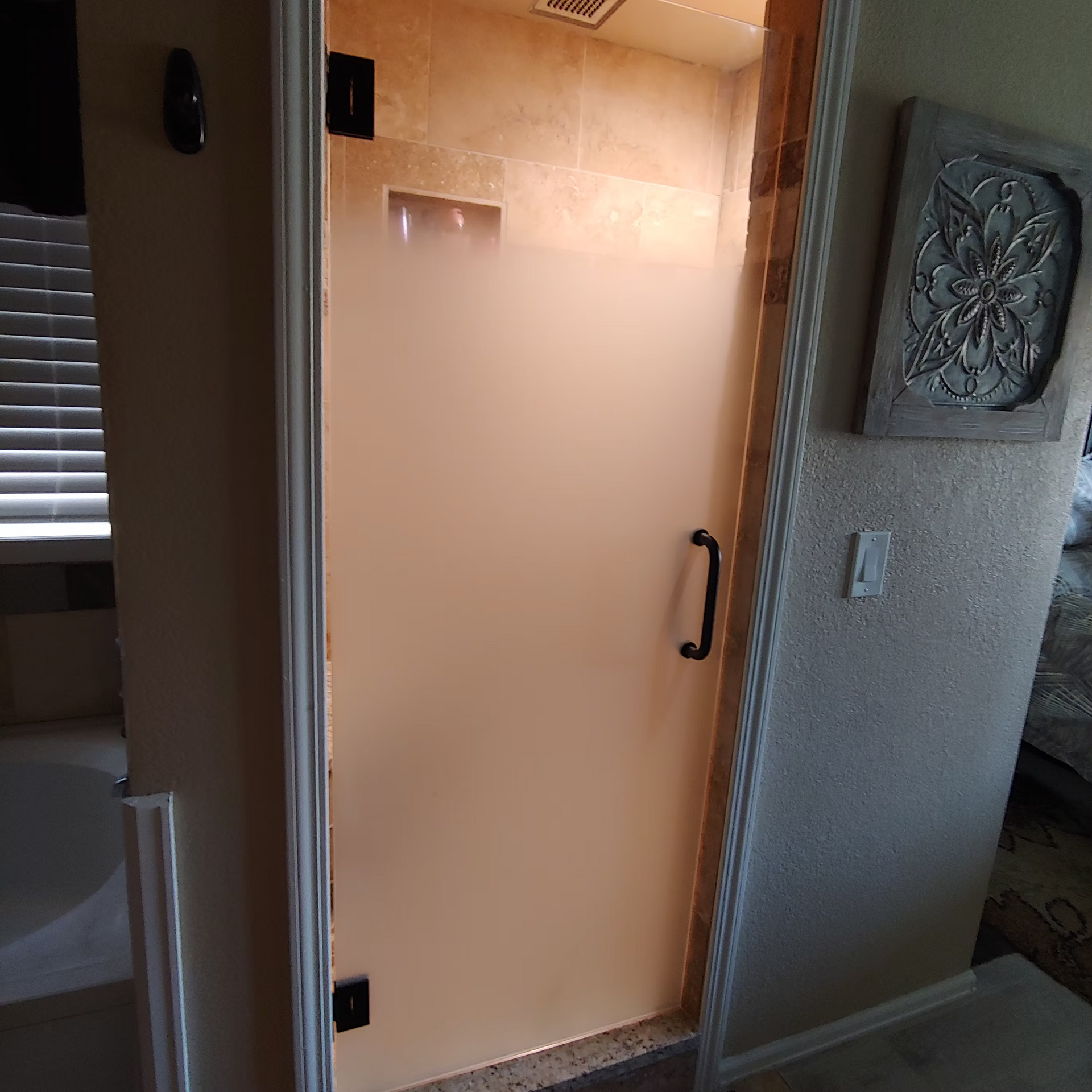 A door in a bathroom with a picture on the wall above it