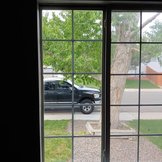 A truck is parked on the side of the road in front of a window.