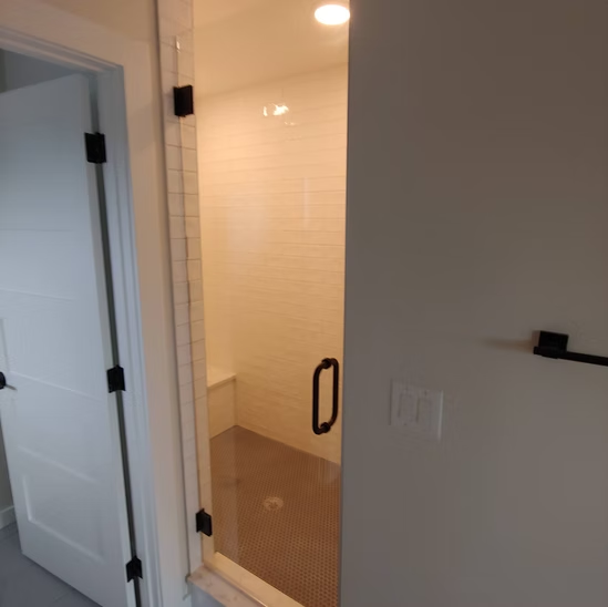 A bathroom with a walk in shower and a glass door.