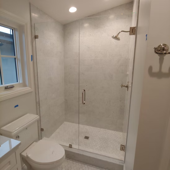 A bathroom with a toilet , shower , and window.