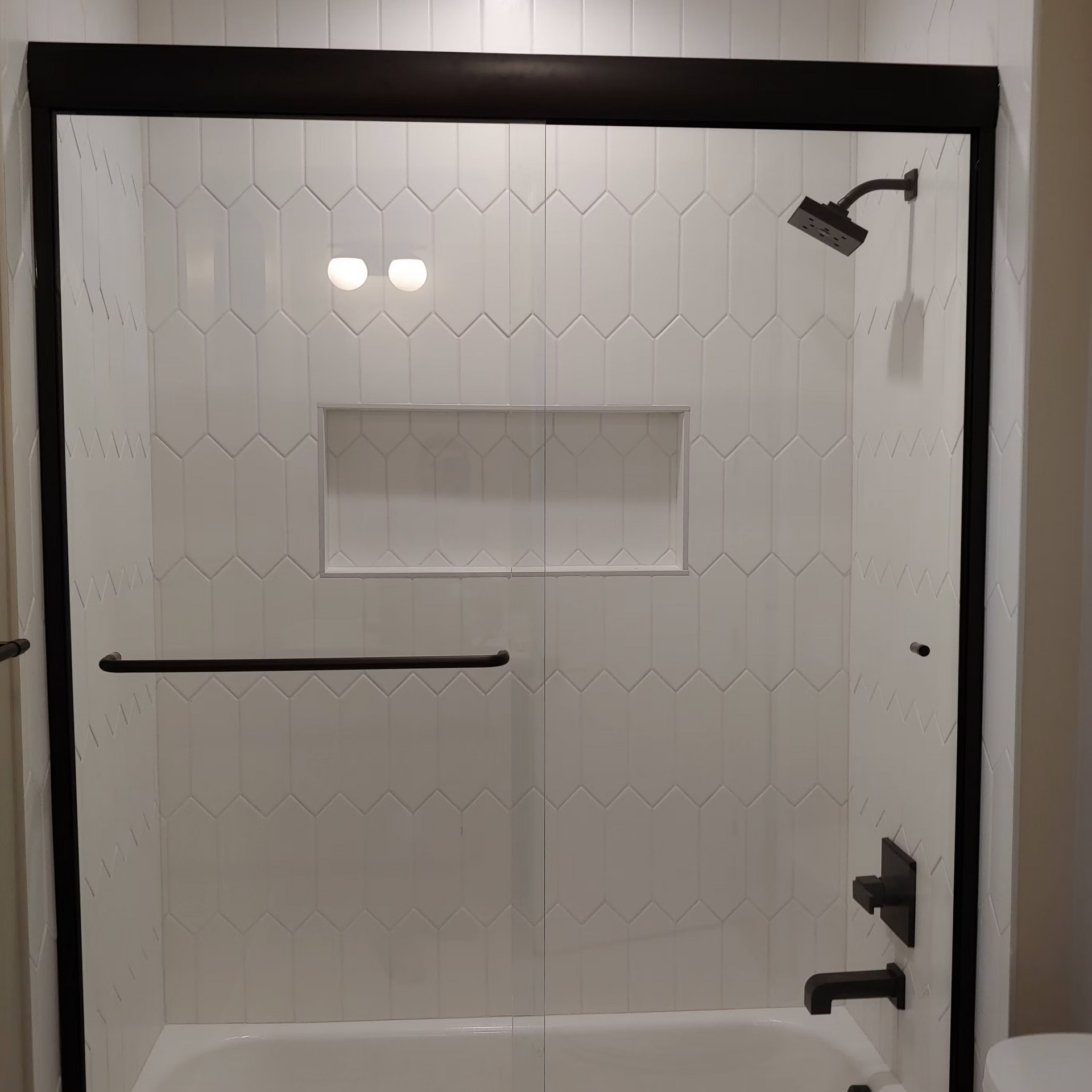 A bathroom with a bathtub and a shower with a sliding glass door.