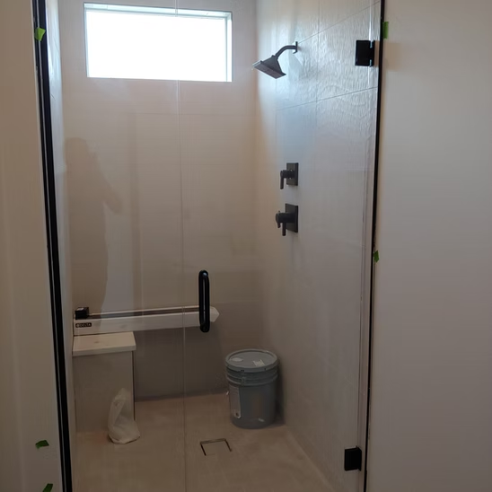 A bathroom with a shower and a bucket on the floor