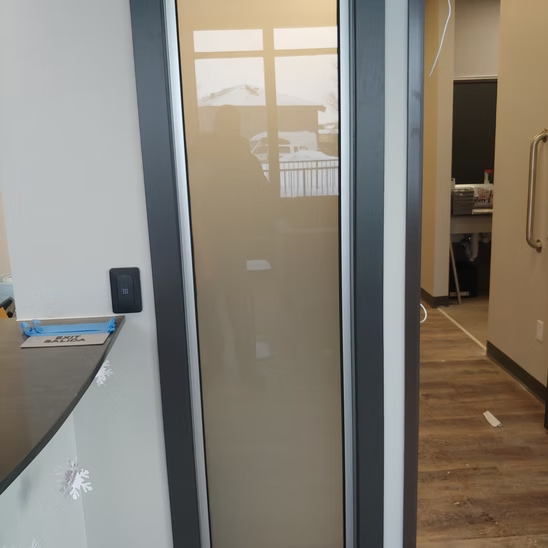 A hallway with a glass door leading to a room.