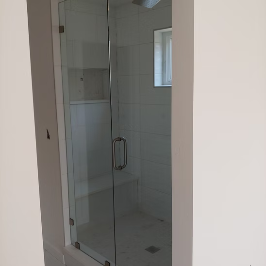 A bathroom with a glass shower door and a window.