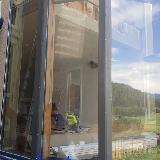 A man is standing in front of a window with a blue tape on it.