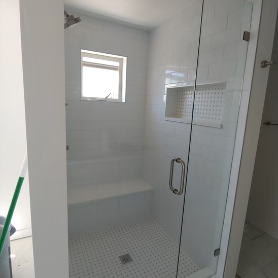 A bathroom with a glass shower door and a window.