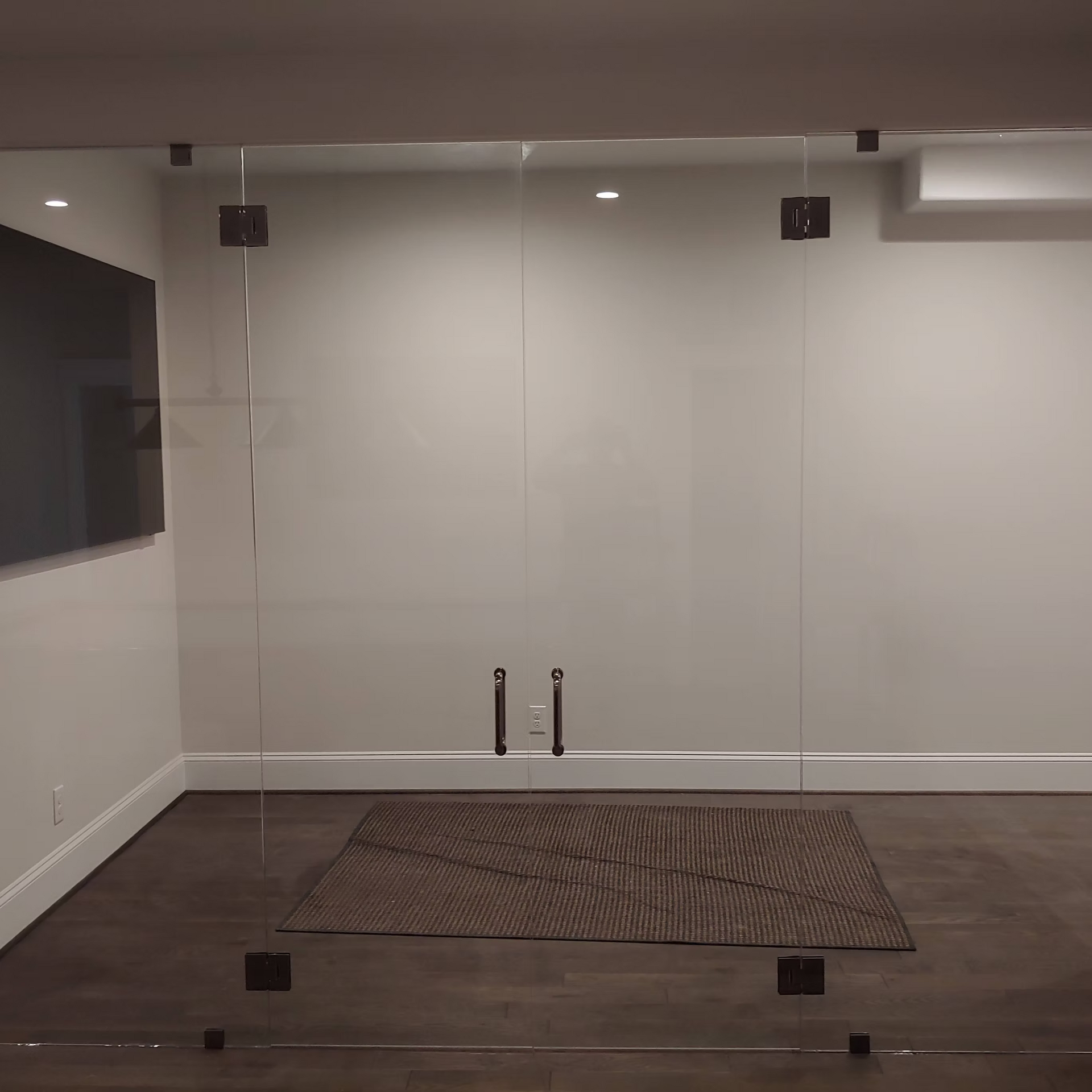 An empty room with a rug and a tv on the wall