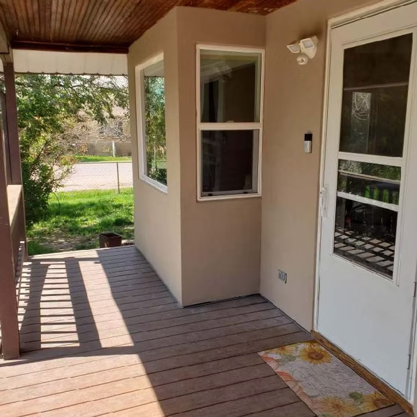 A porch with a white door and two windows