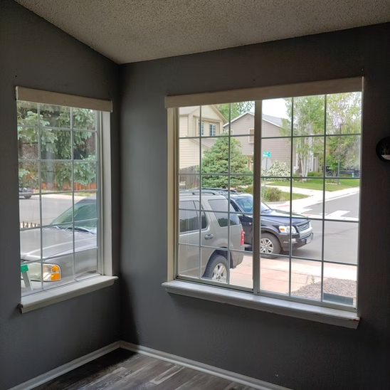A room with two windows and a car in the window