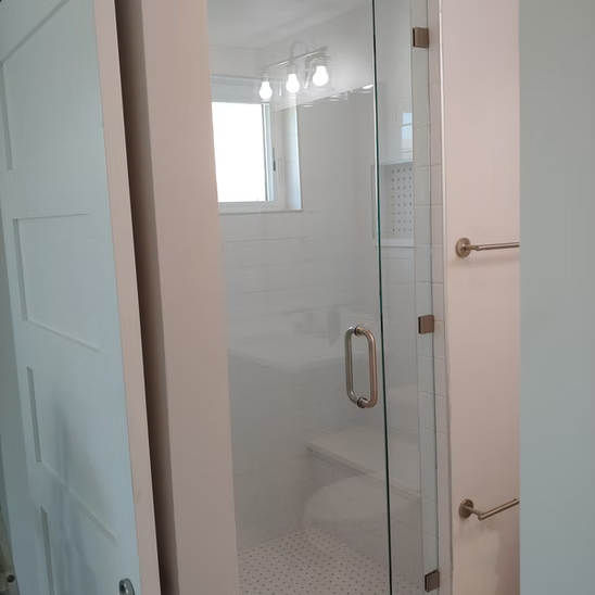 A bathroom with a glass shower door and a toilet.
