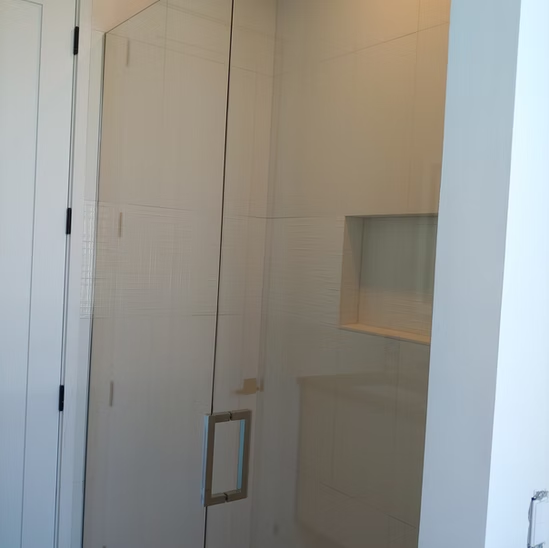 A bathroom with a glass door and white cabinets