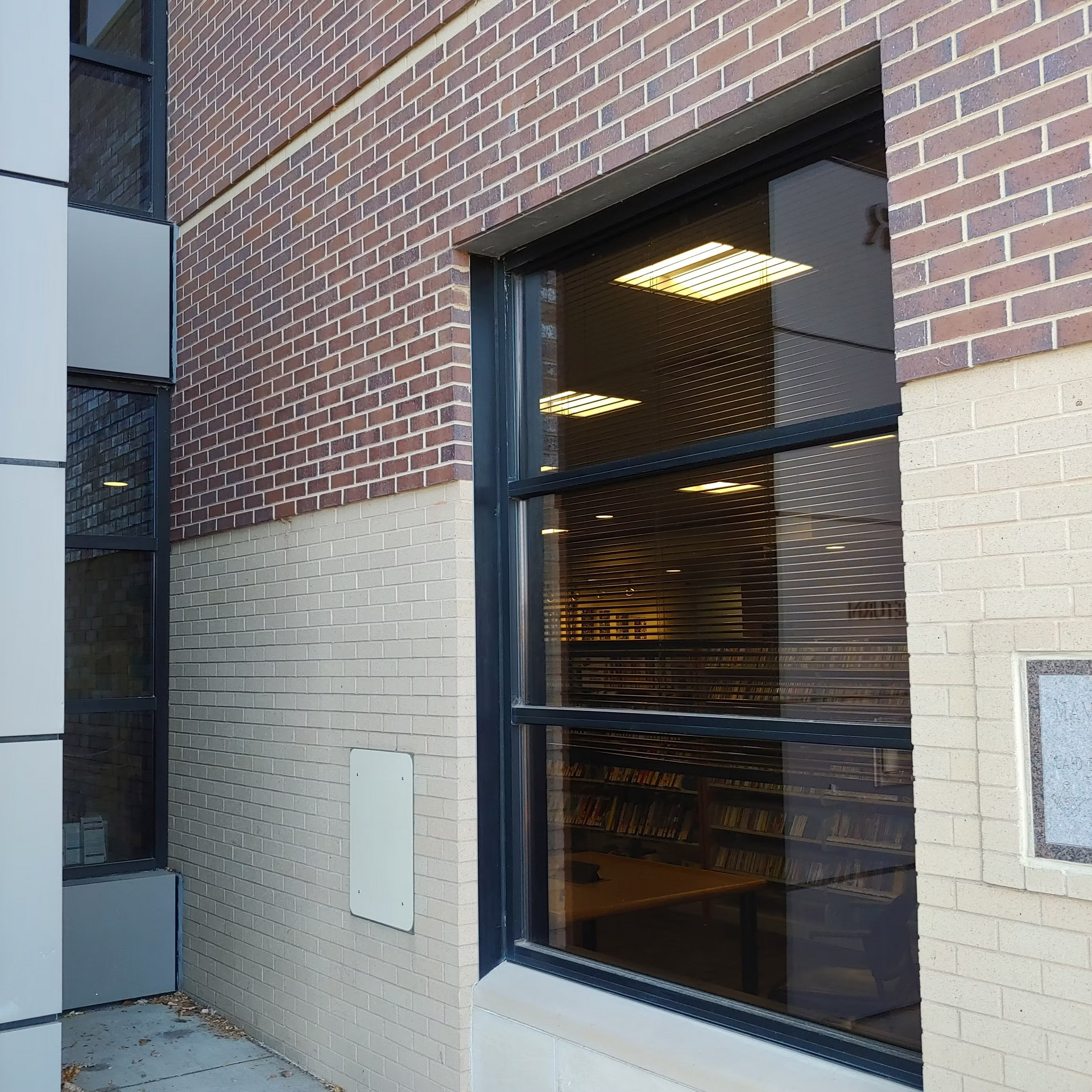 A brick building with a large window with a black frame