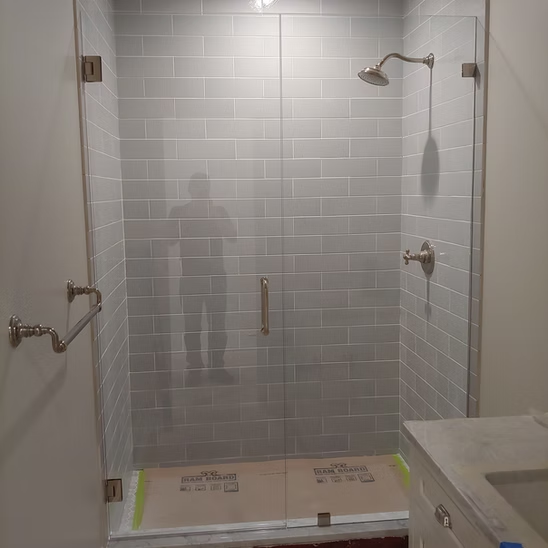 A bathroom with a glass shower door and a sink.