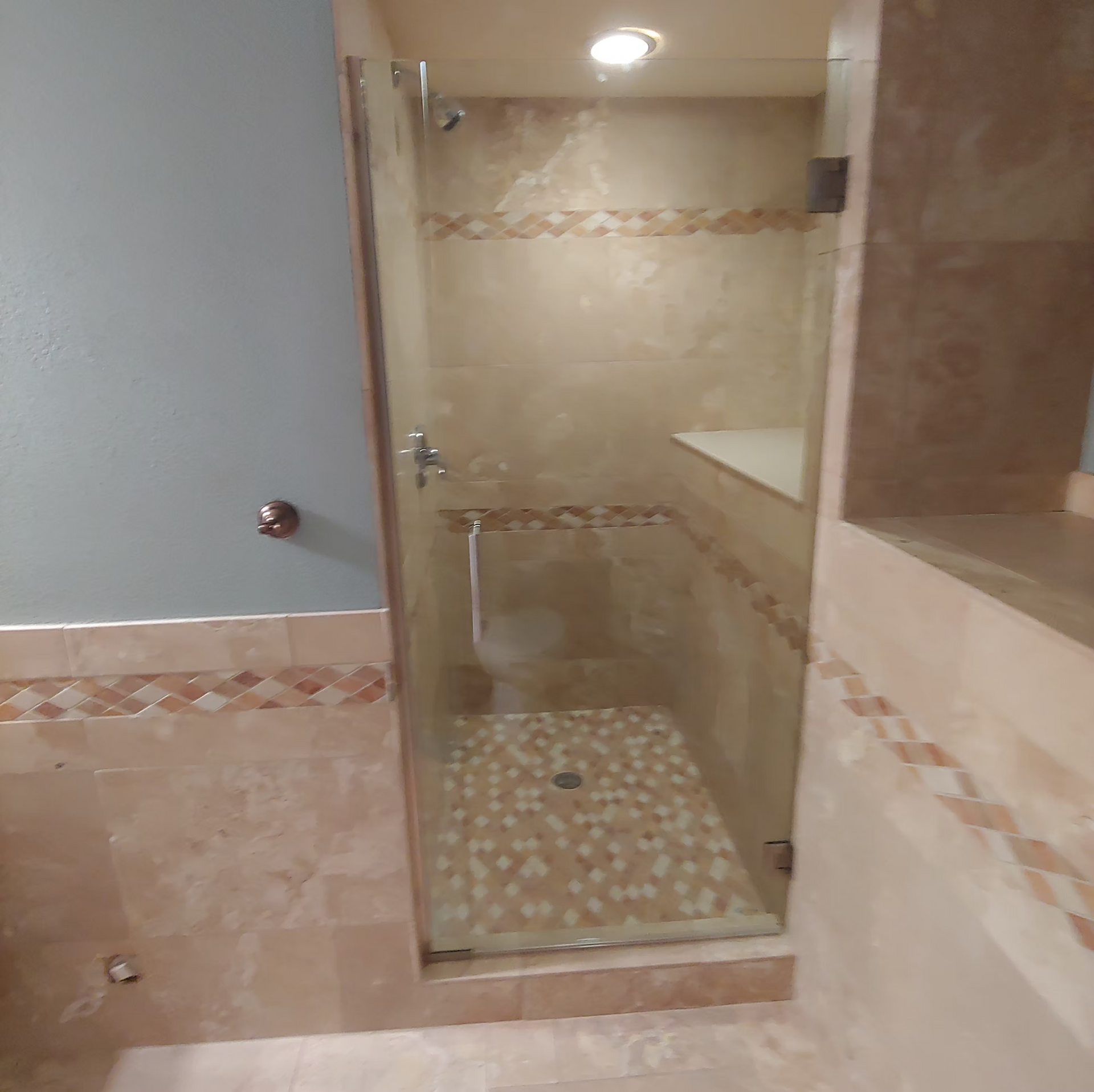 A bathroom with a walk in shower with a glass door.