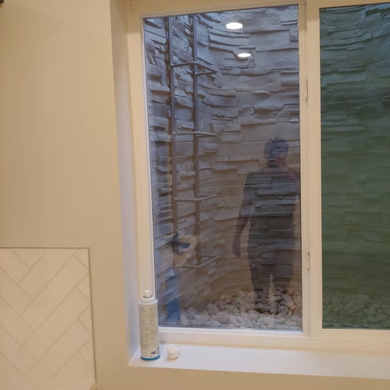 A man is standing in front of a window in a bathroom.