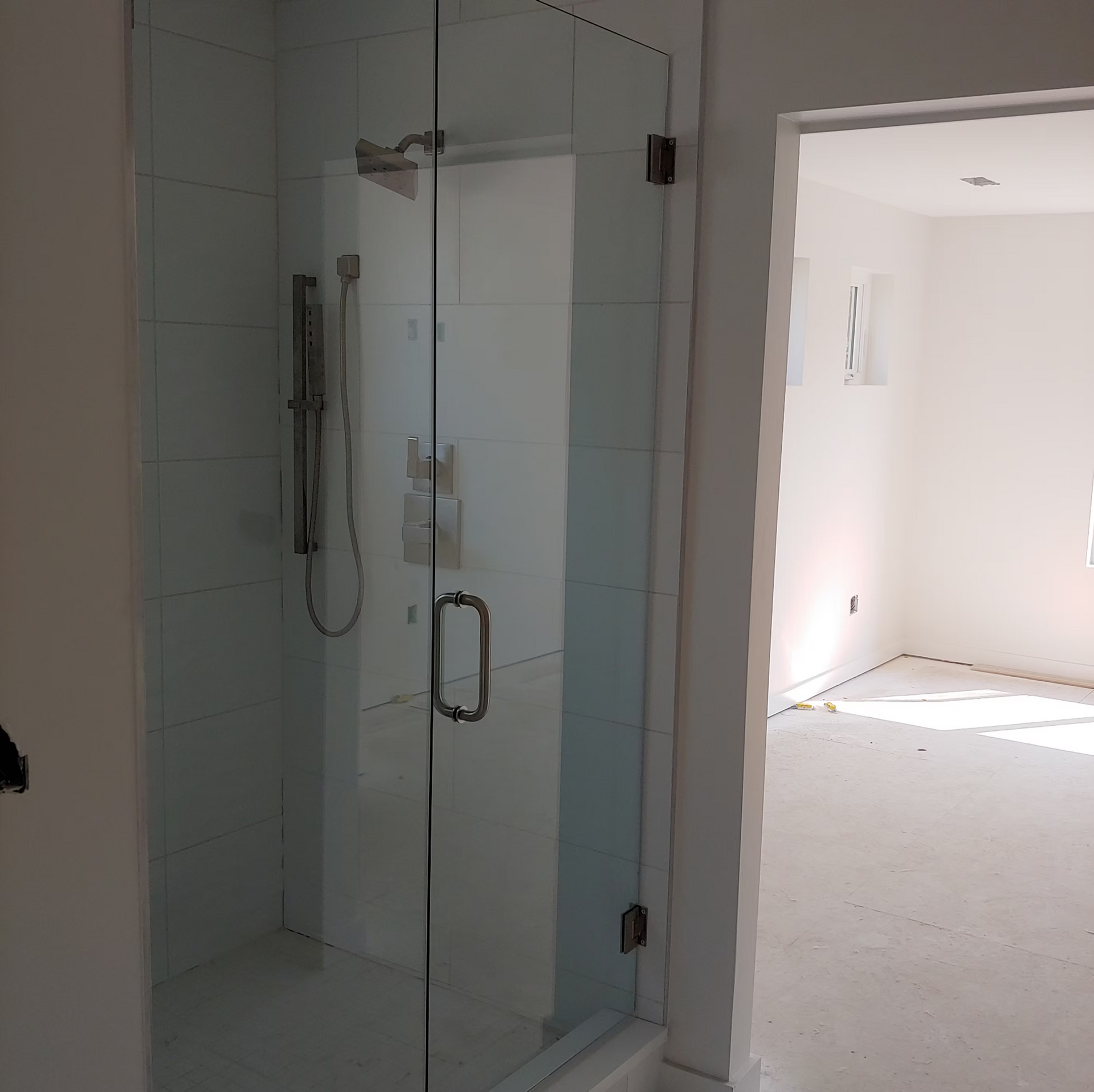 A bathroom with a glass shower door and a shower head