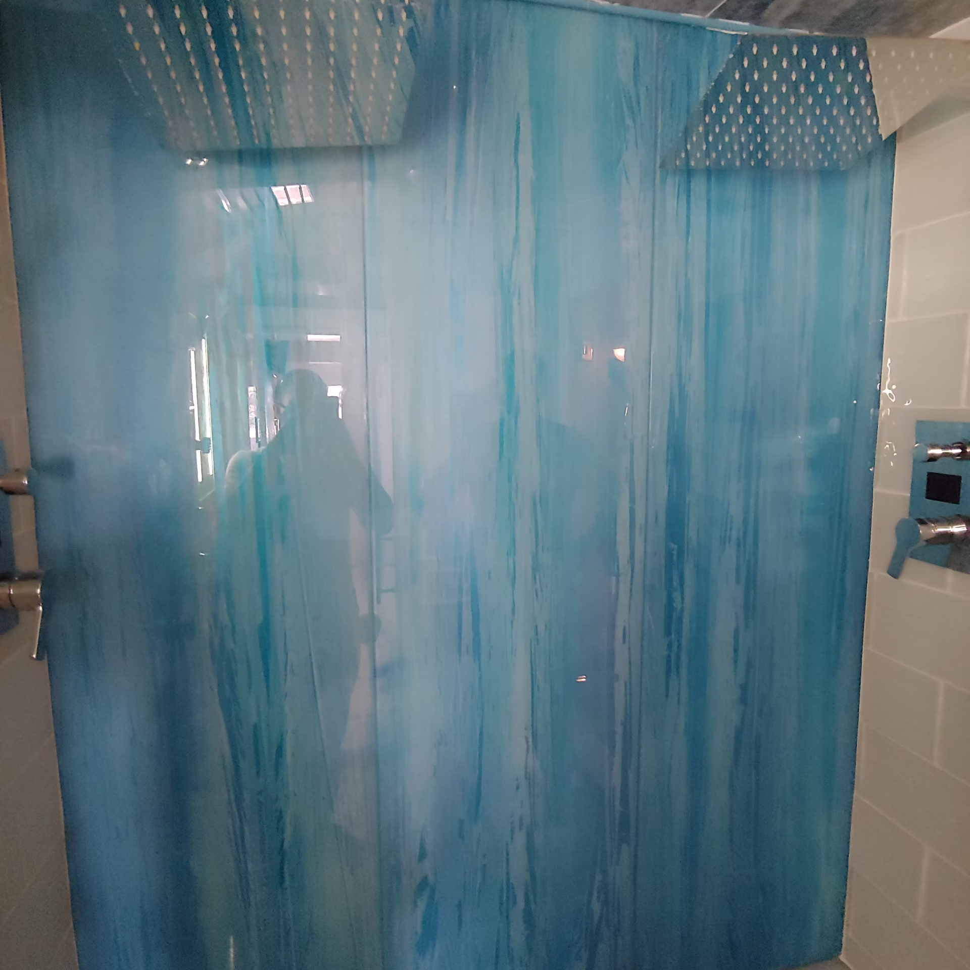 A blue shower curtain is hanging in a bathroom next to a shower head.