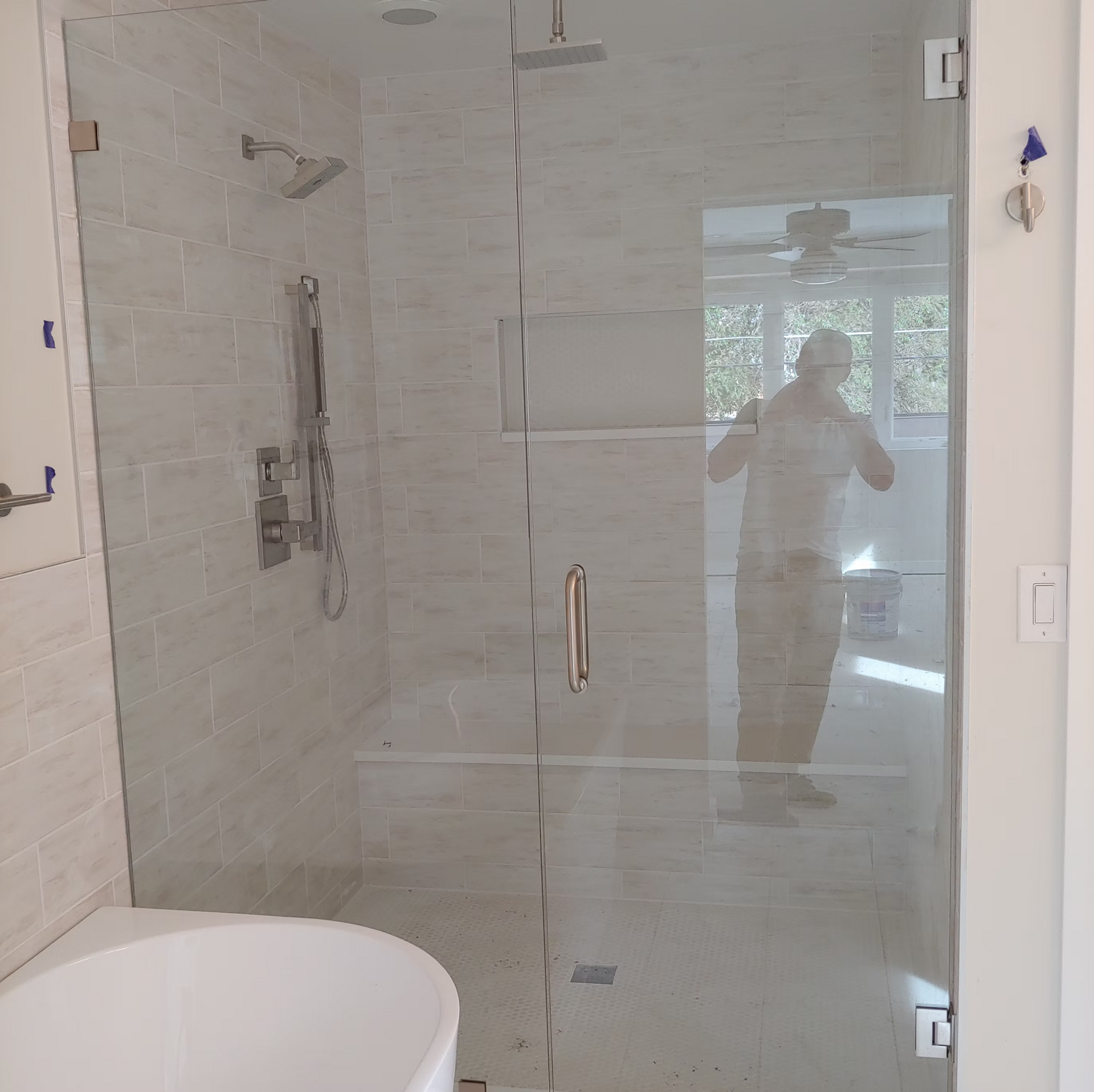 A man is taking a picture of himself in a bathroom with a glass shower door.
