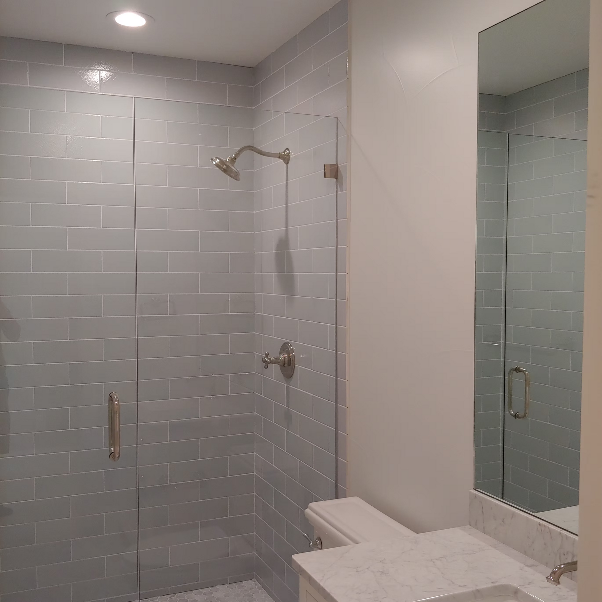 A bathroom with a walk in shower and a sink