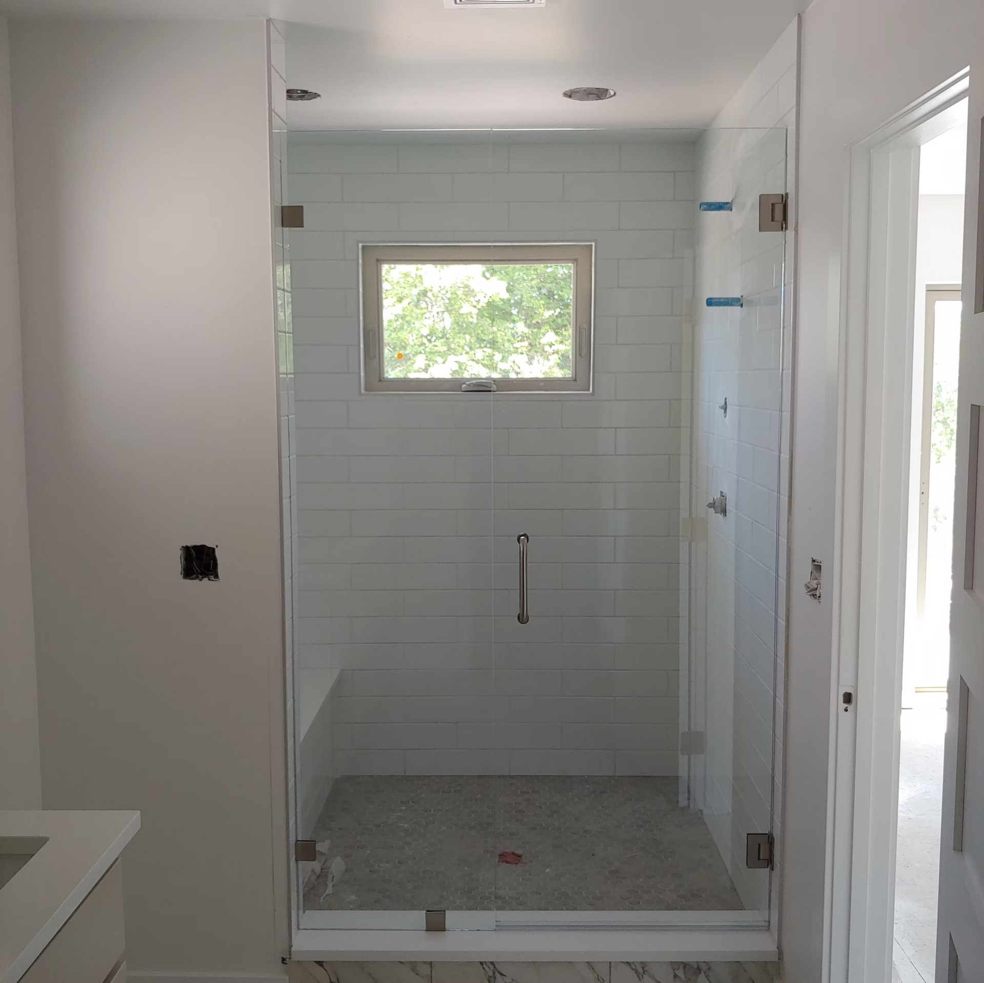 A bathroom with a glass shower door and a window.