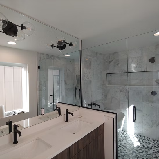 A bathroom with two sinks , a shower and a large mirror.