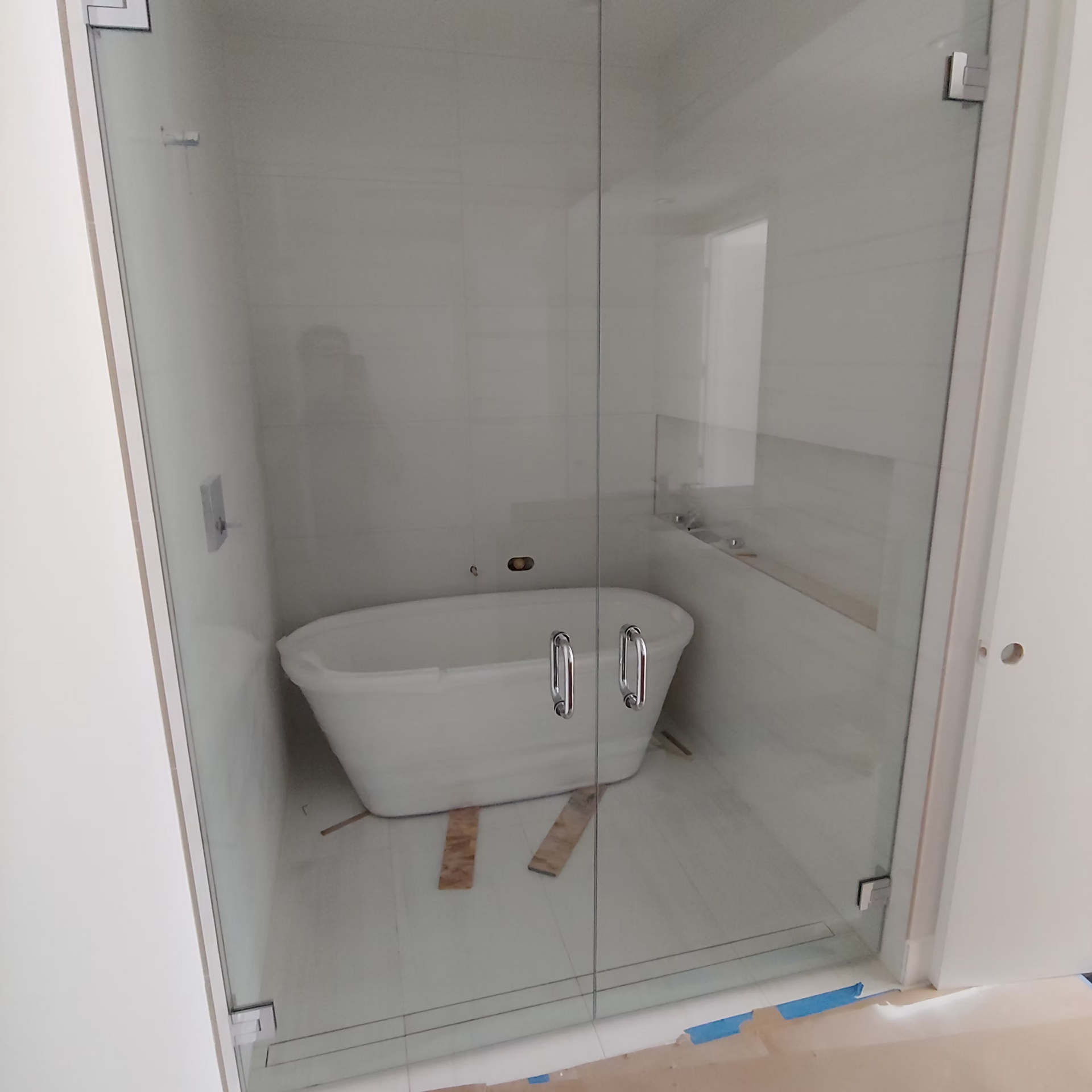 A bathtub is sitting inside of a glass shower stall.