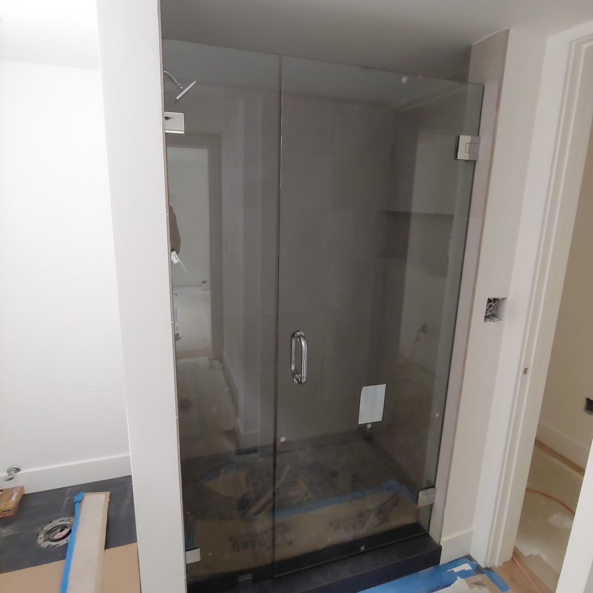 A glass shower door is being installed in a bathroom.