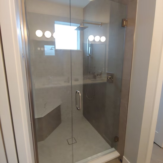 A bathroom with a glass shower door and a sink.