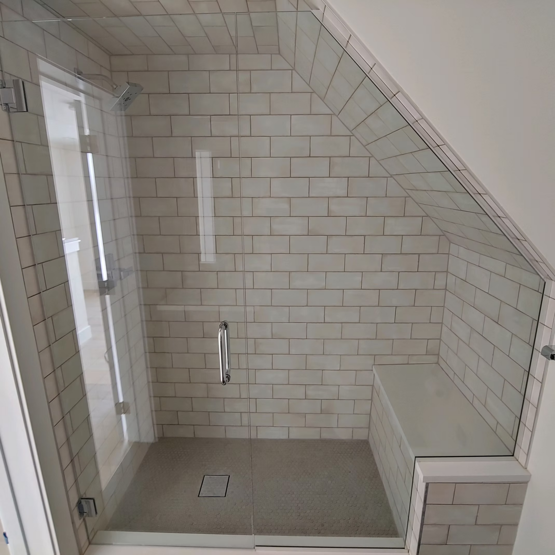 A bathroom with white tiles and a glass shower door