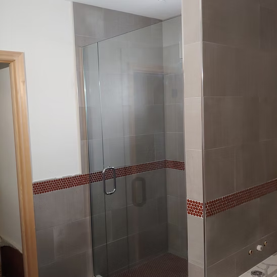 A bathroom with a walk in shower with a glass door