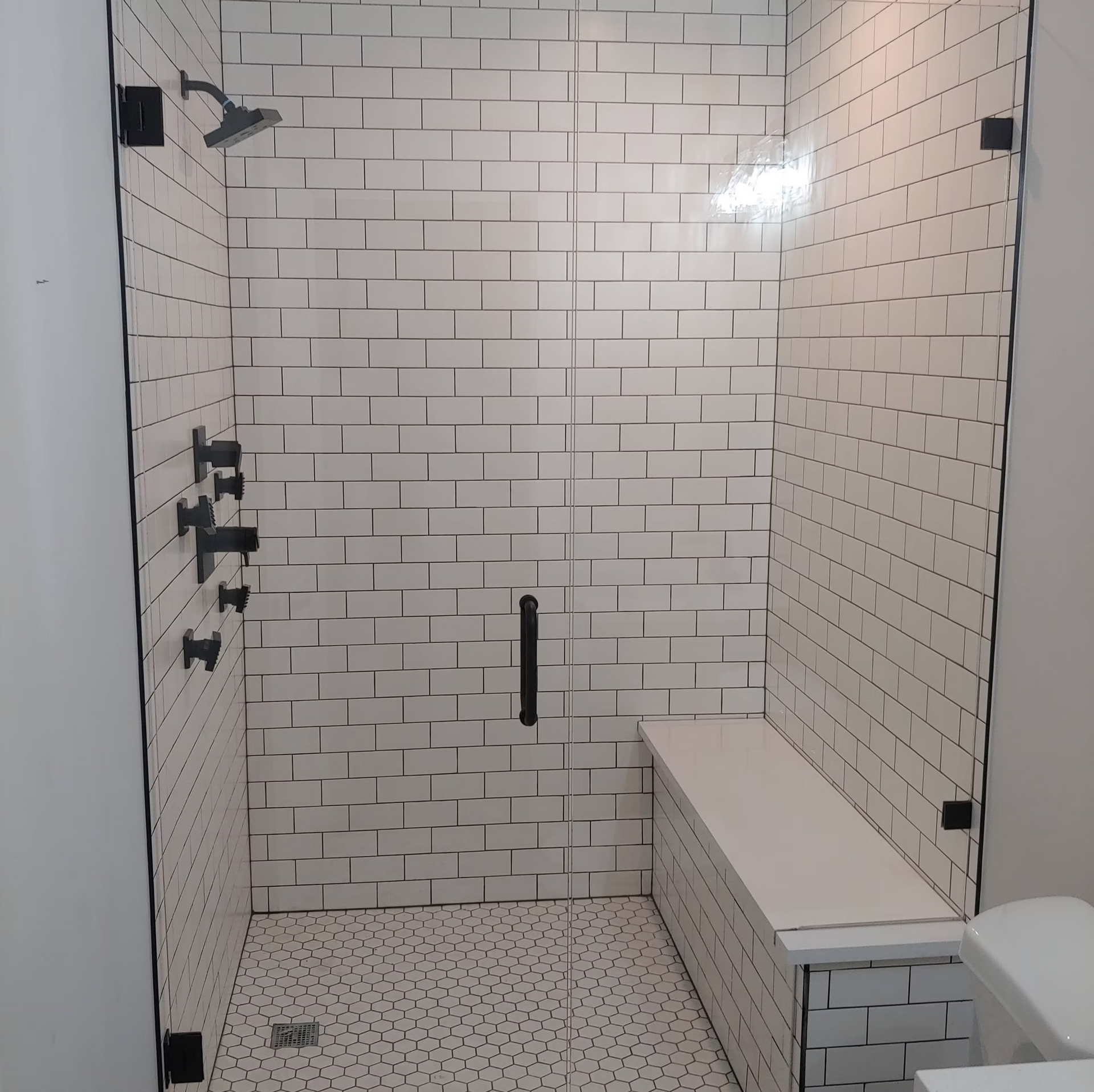 A bathroom with white brick walls and a glass shower door