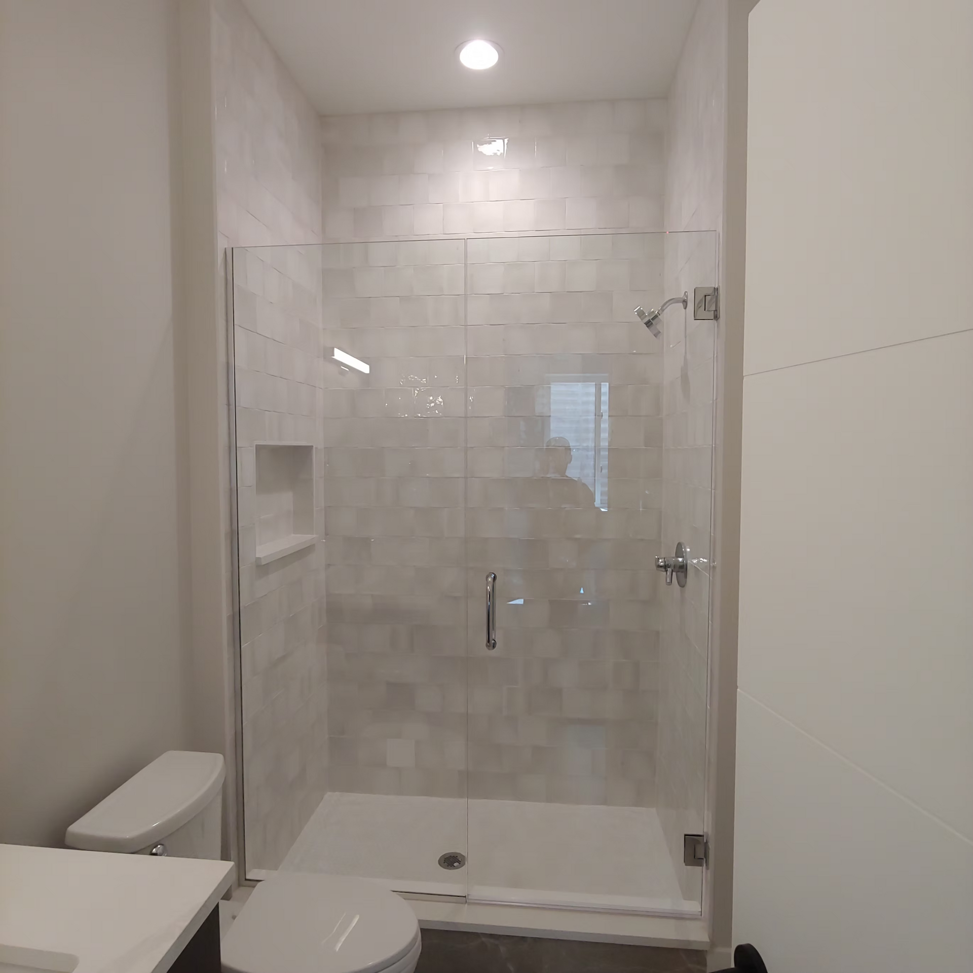 A bathroom with a toilet , sink , shower and glass door.