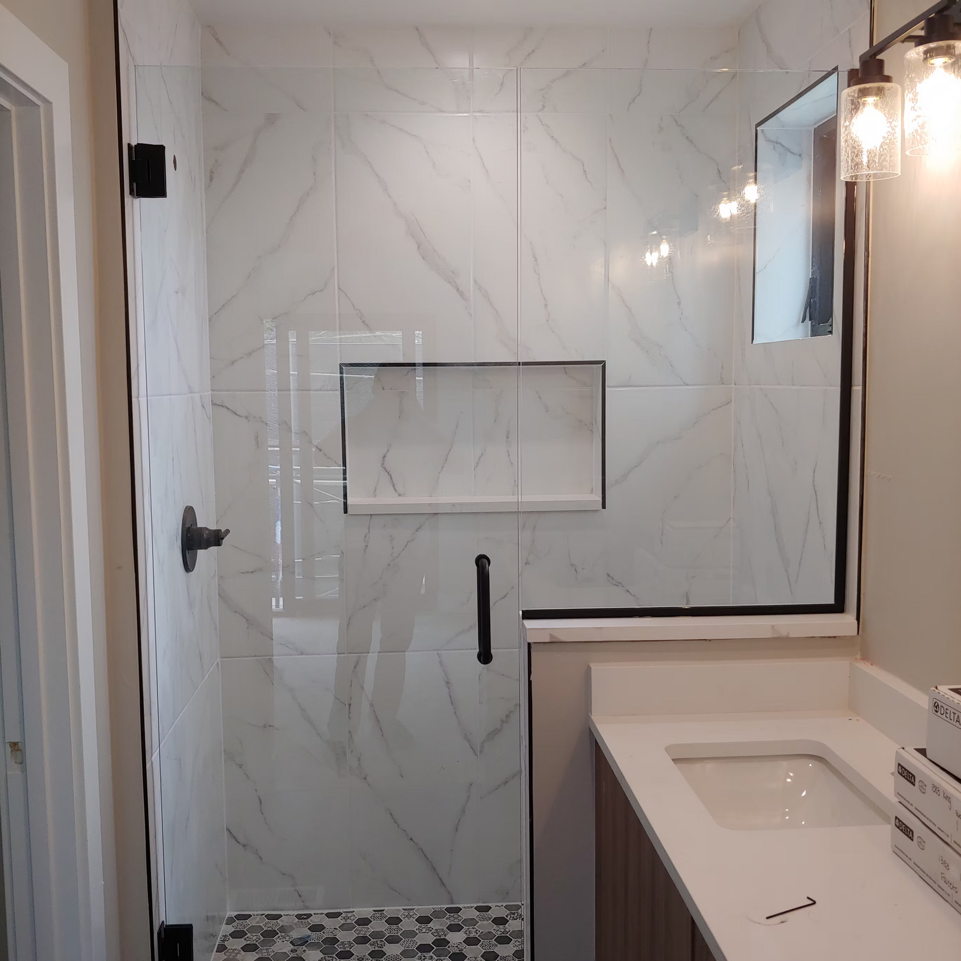 A bathroom with a glass shower door and a sink