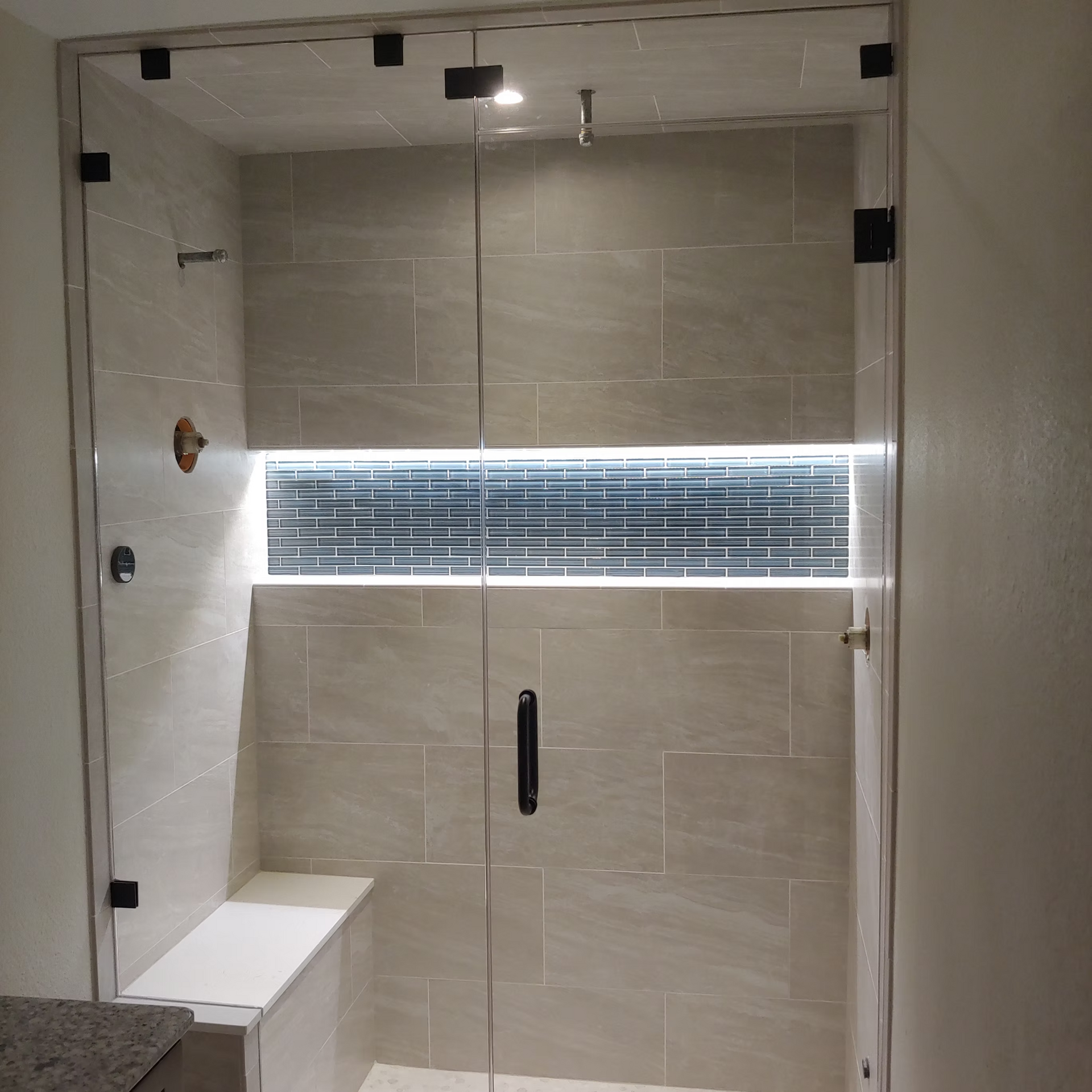 A bathroom with a glass shower door and a window.