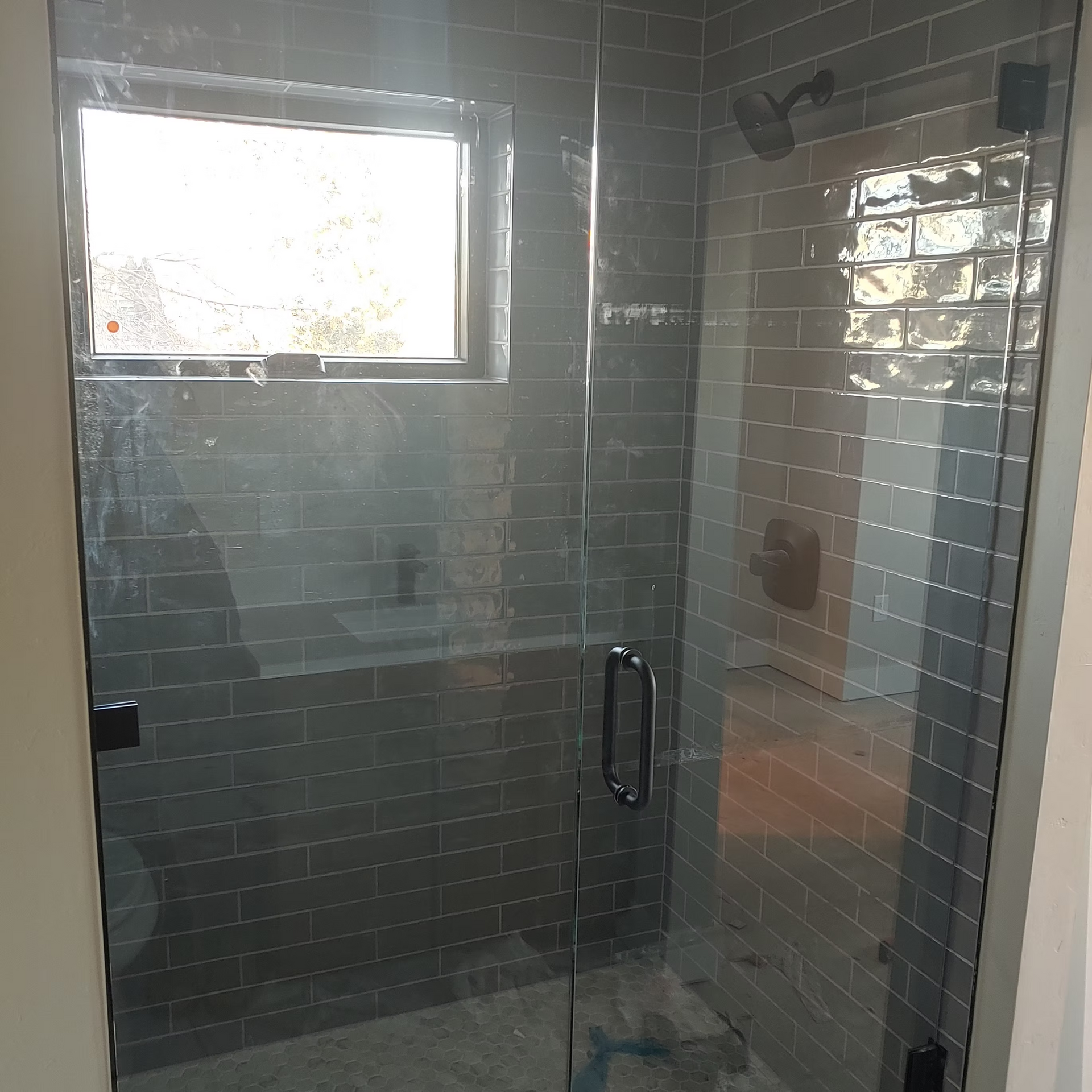 A bathroom with a glass shower door and a window.