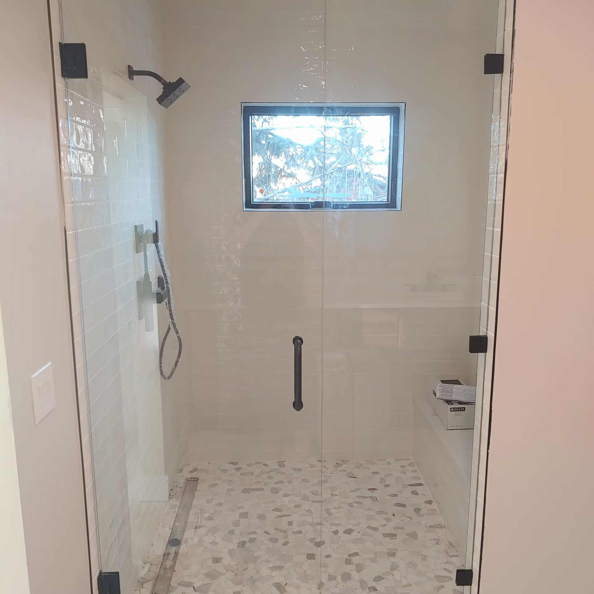 A bathroom with a walk in shower and a window.
