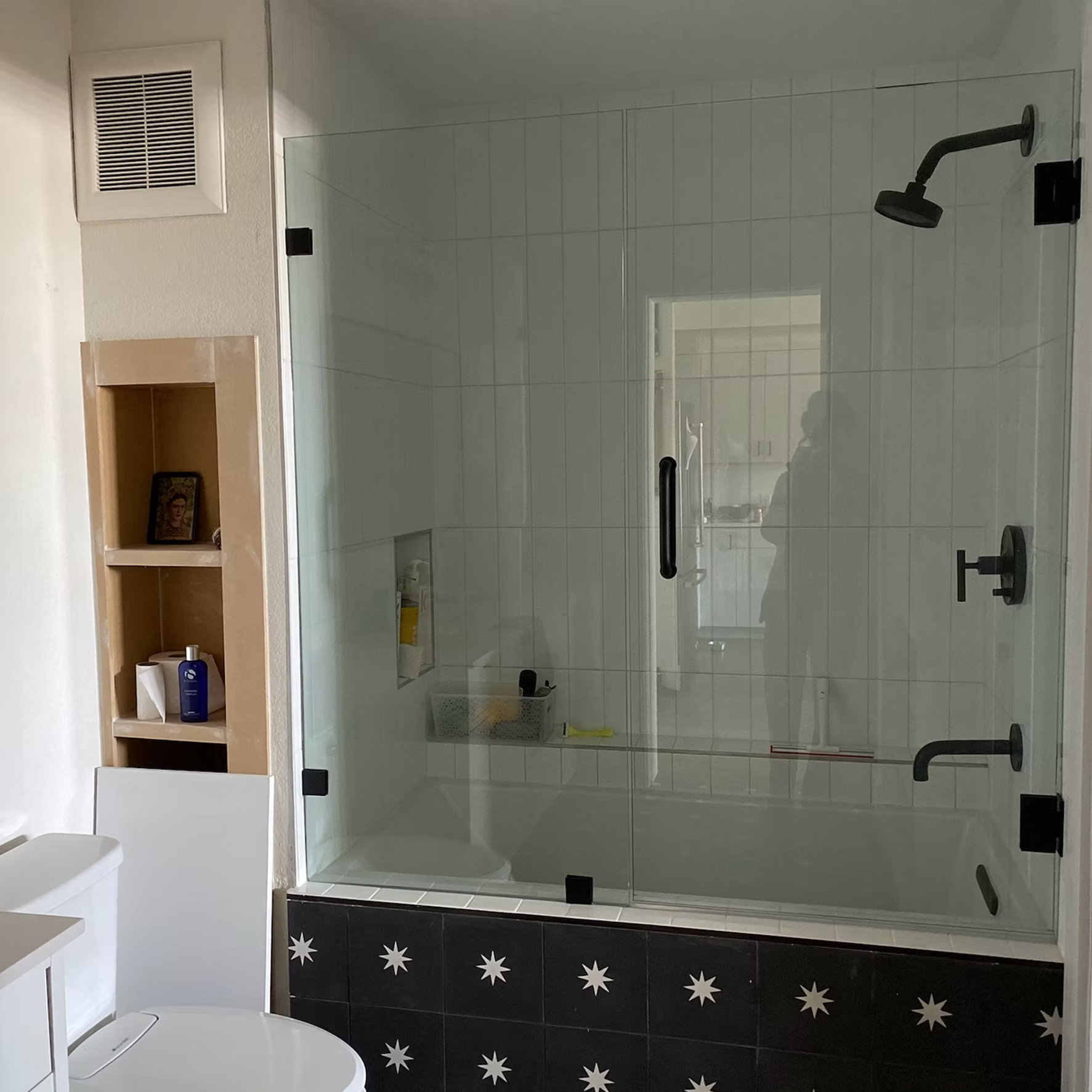 A bathroom with a glass shower door and a toilet