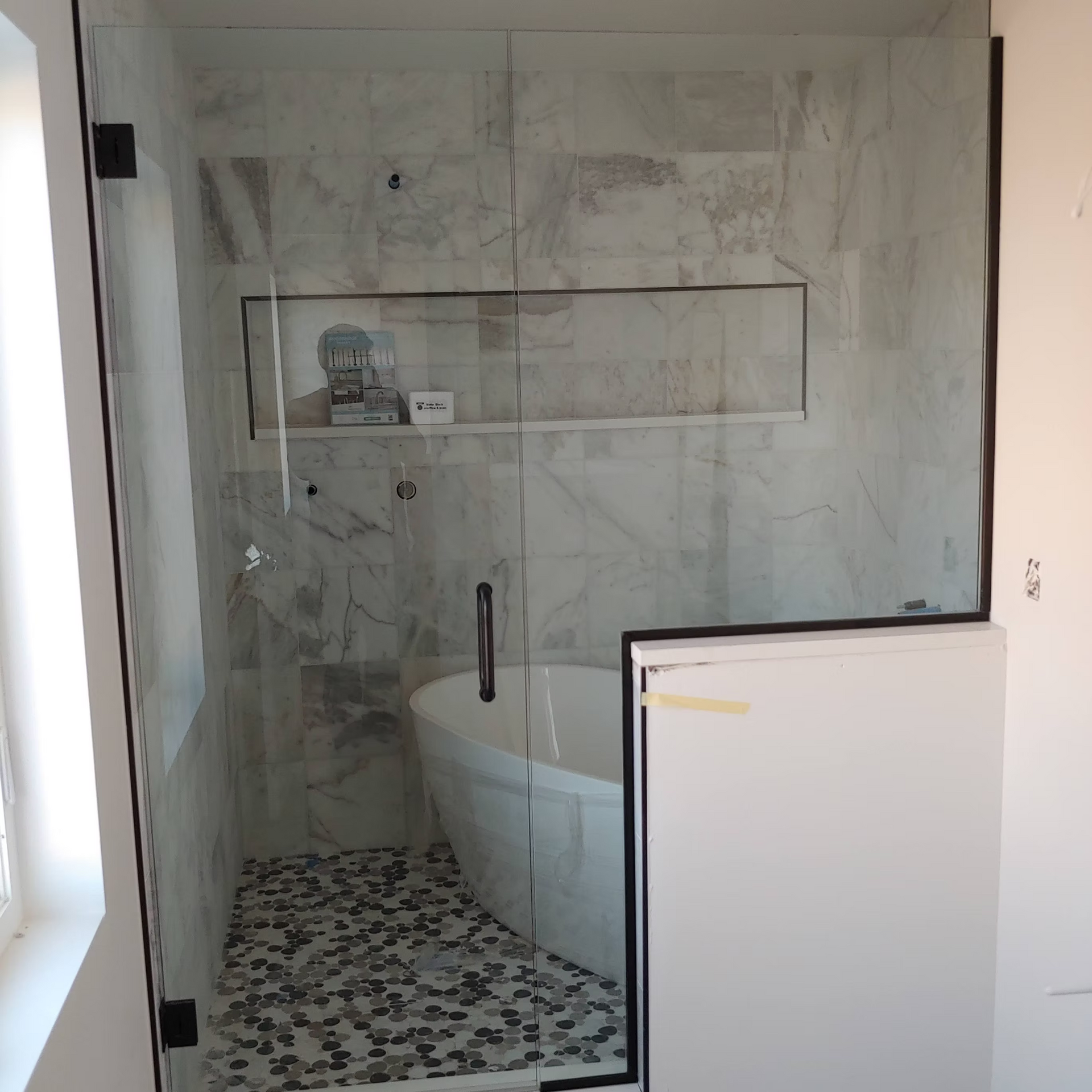 A bathroom with a tub and a shower with a glass door