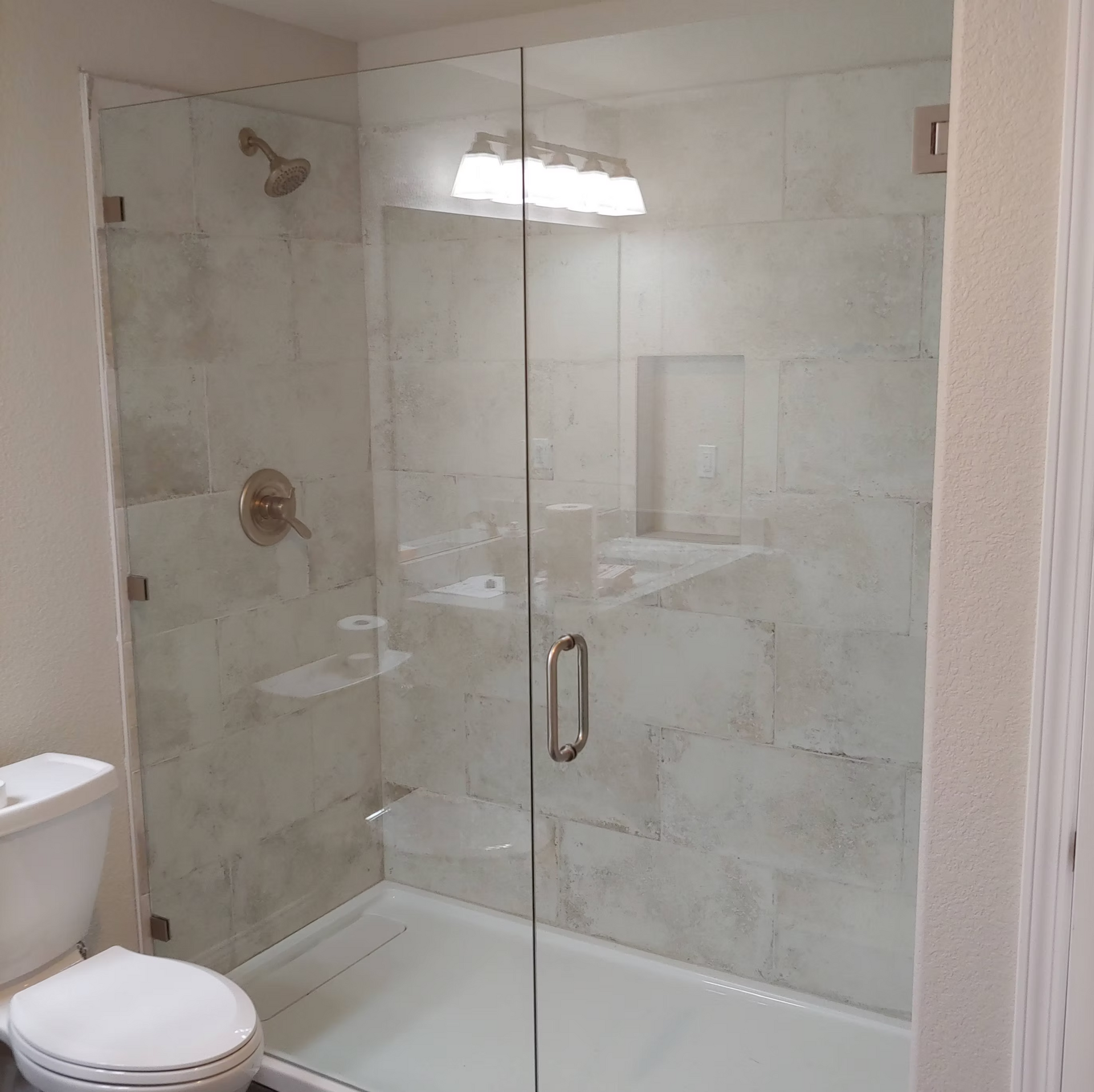 A bathroom with a toilet and a glass shower door