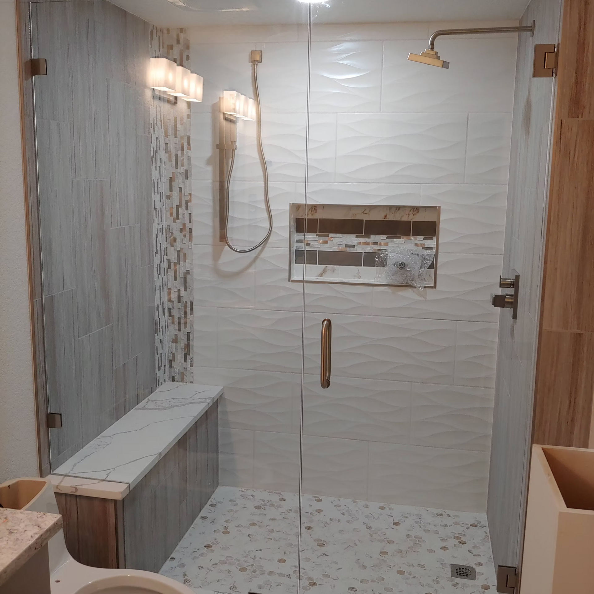 A bathroom with a walk in shower with a glass door