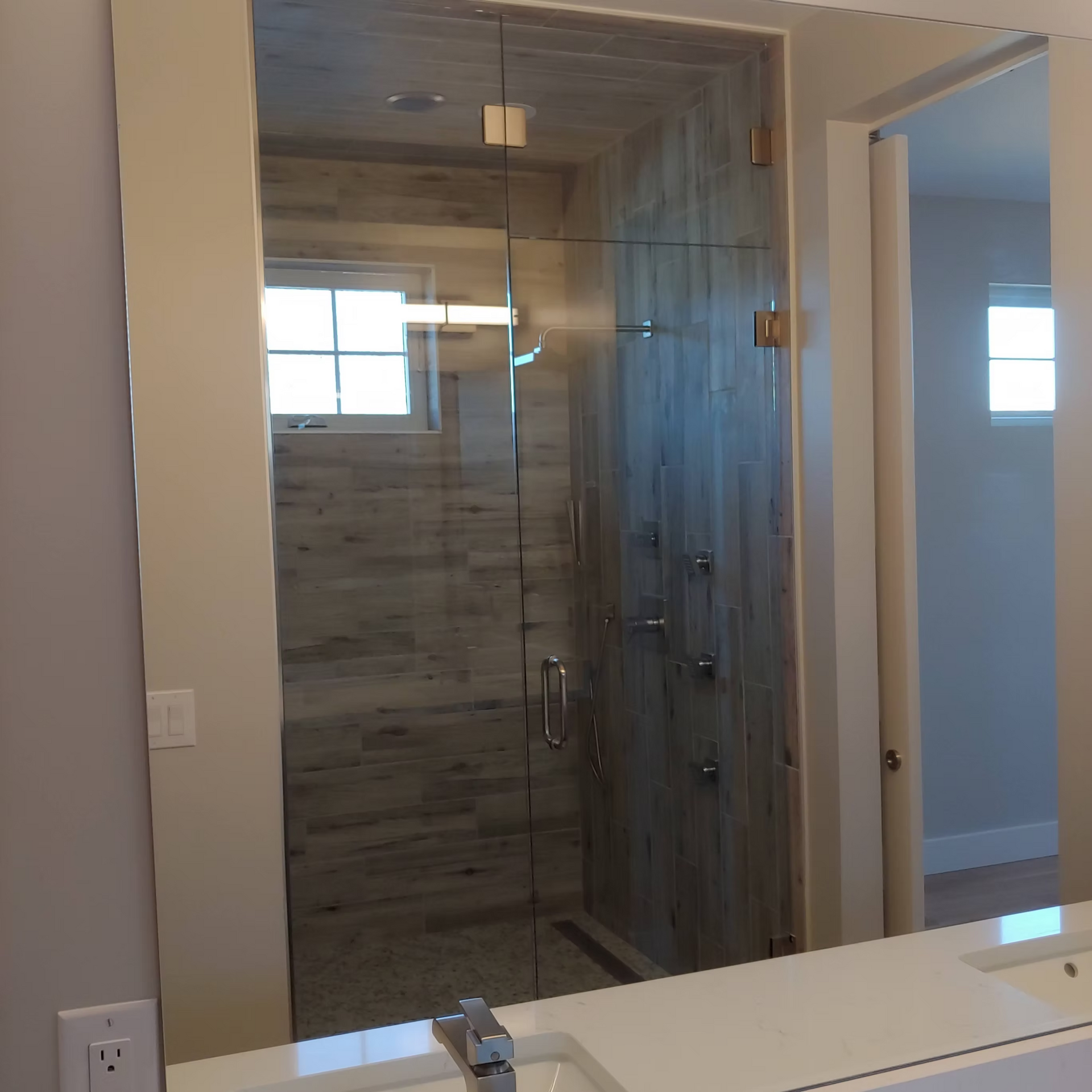 A bathroom with a glass shower door and a sink