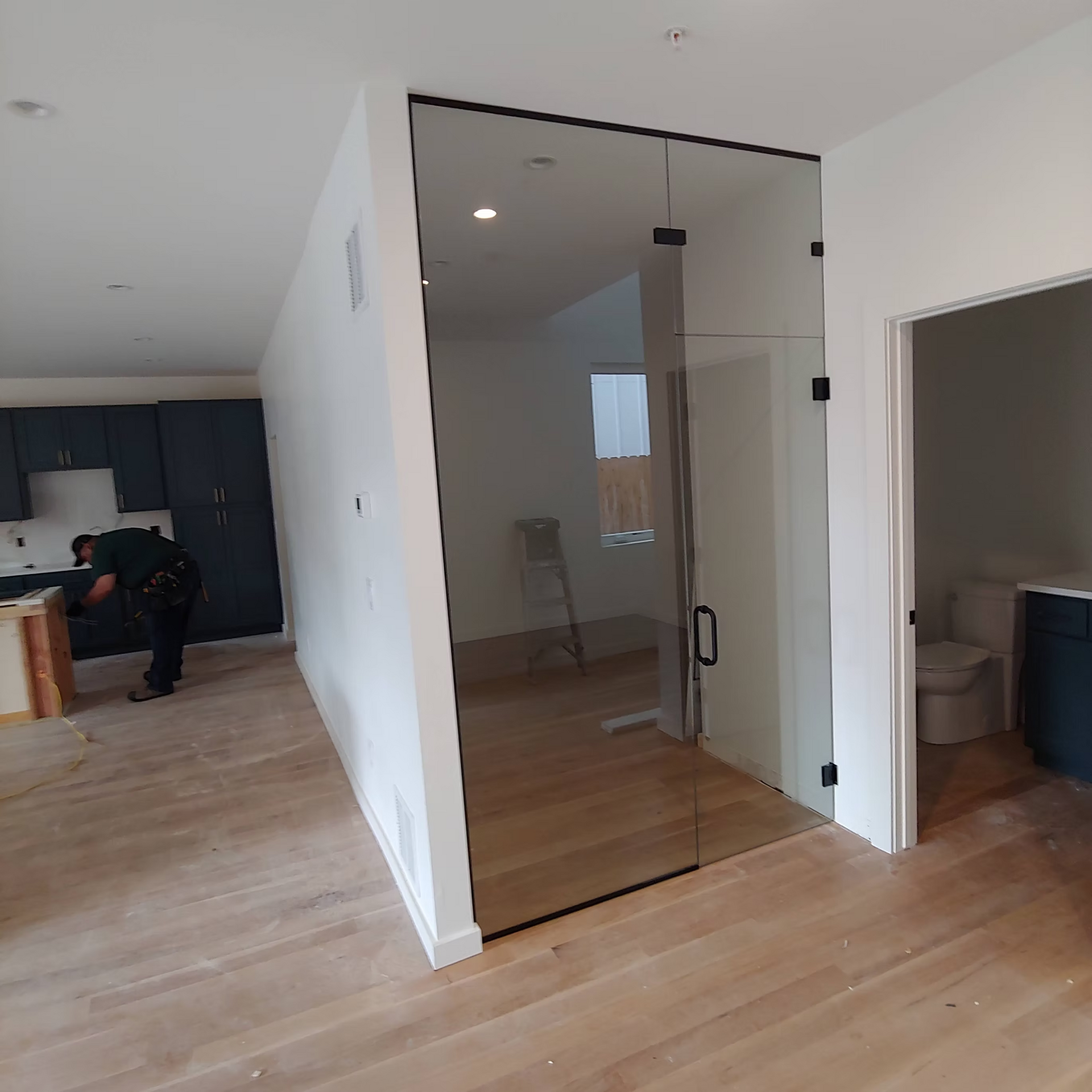 A man is standing in a room next to a glass door.