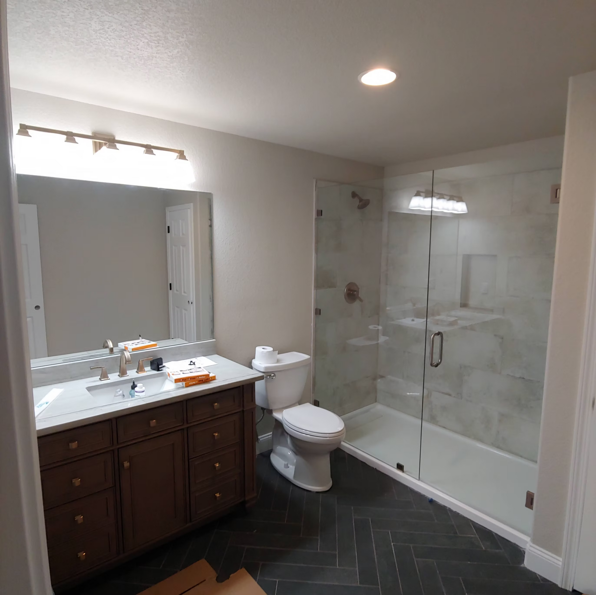 A bathroom with a toilet , sink , shower and mirror.