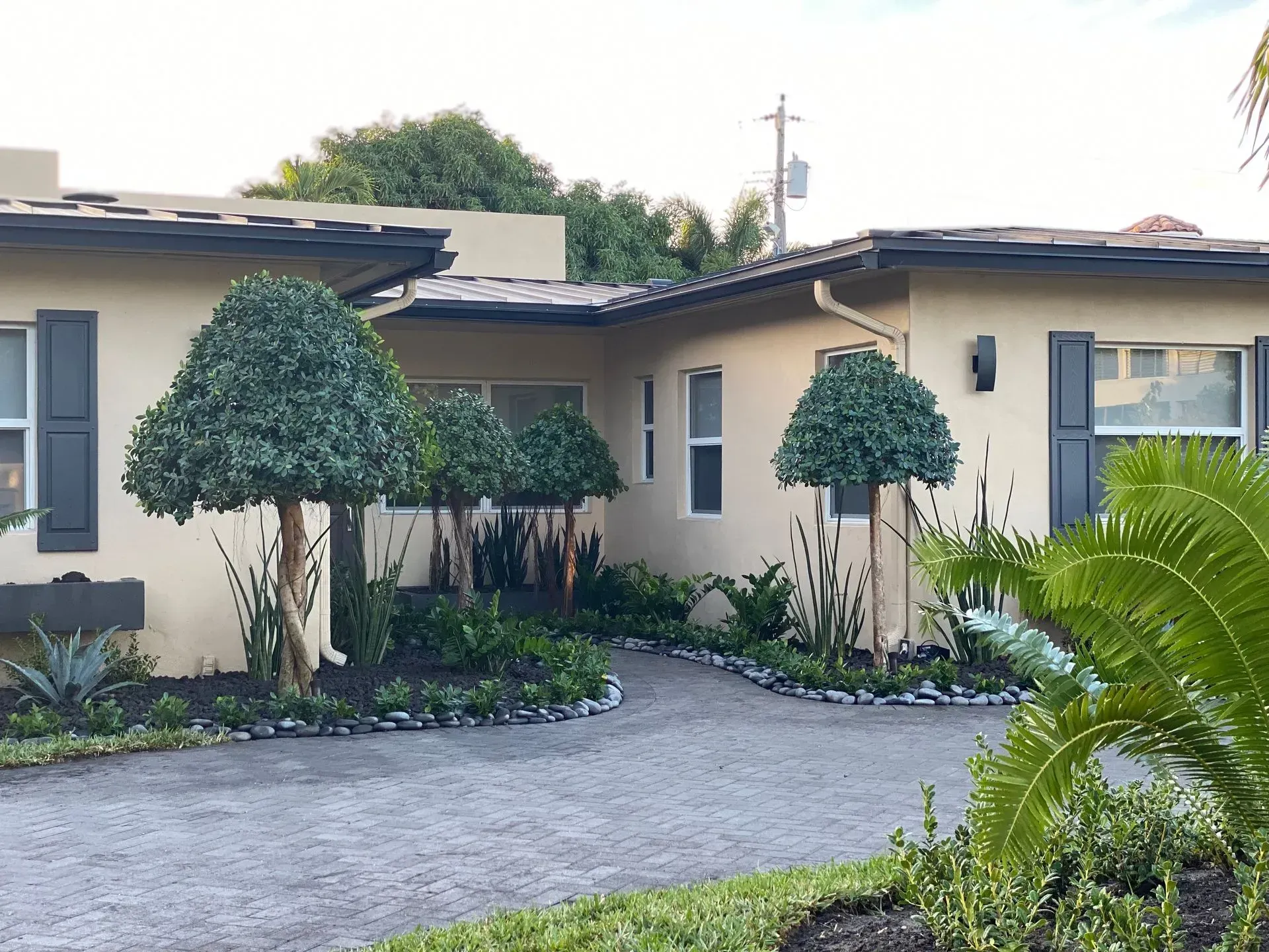 Beige house with manicured landscaping and a curved driveway.