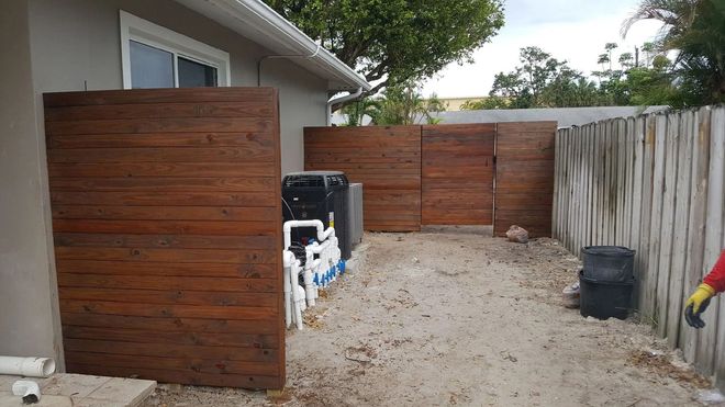Enclosed outdoor area with wood-look walls. Gravel ground, equipment, and a weathered fence.