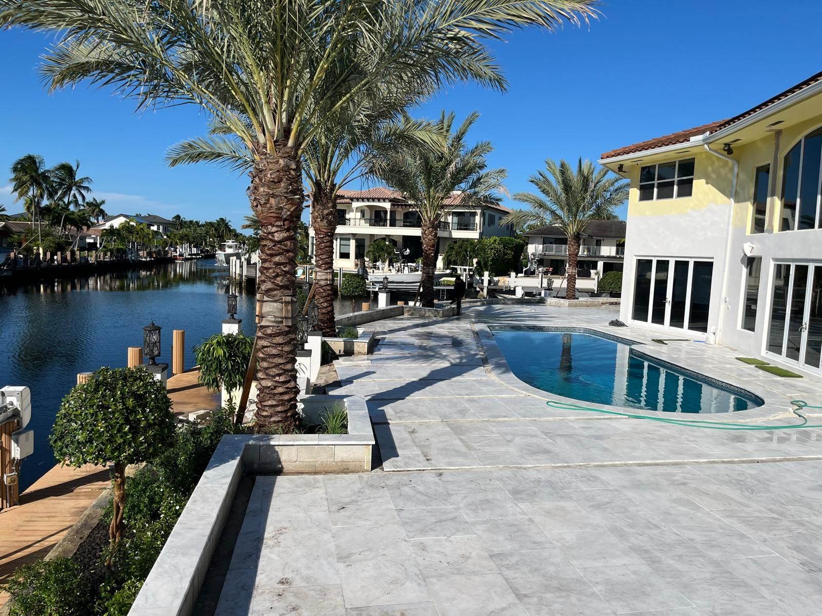 Backyard patio with wooden deck, awning, seating, and green lawn.