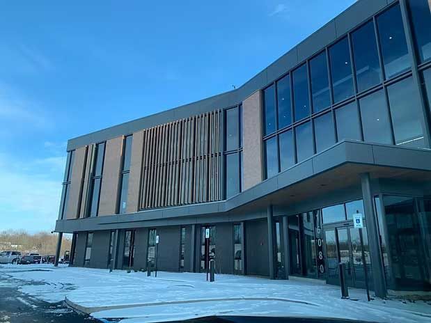 Modern building with large windows, snow-covered ground, and blue sky.